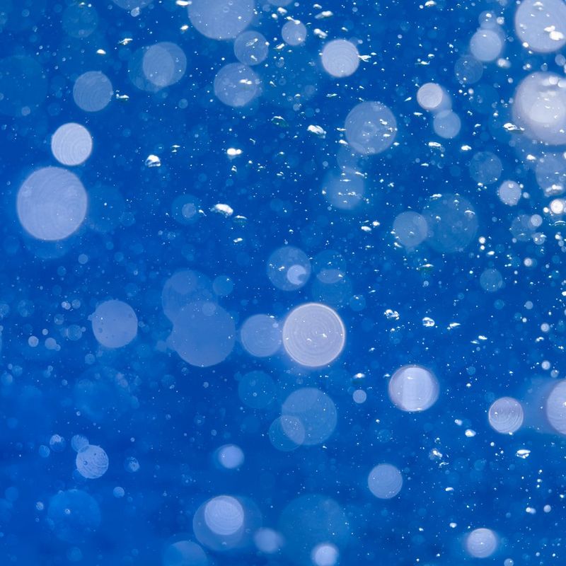 Primo piano di bolle, in diverse sfumature di blu, sotto la superficie del Mar Rosso.