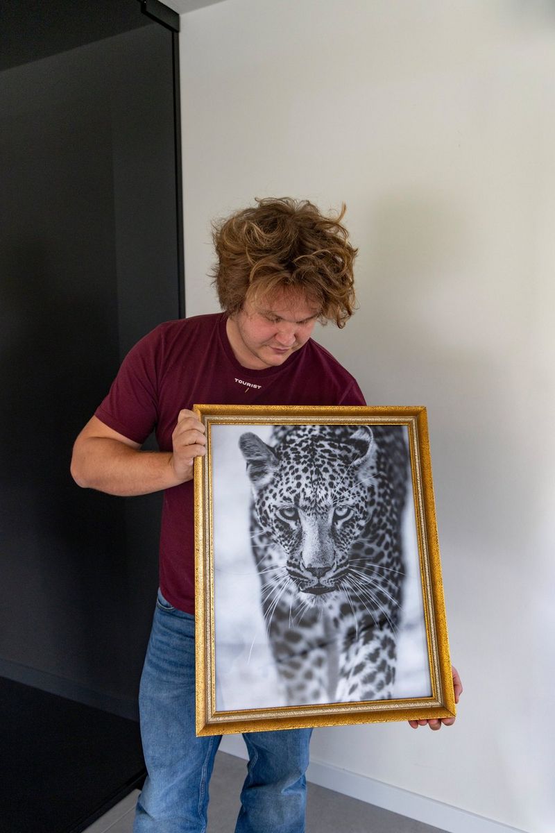 Timo Beke holds a framed black-and-white photo print of a leopard, created using a Canon large-format printer.   