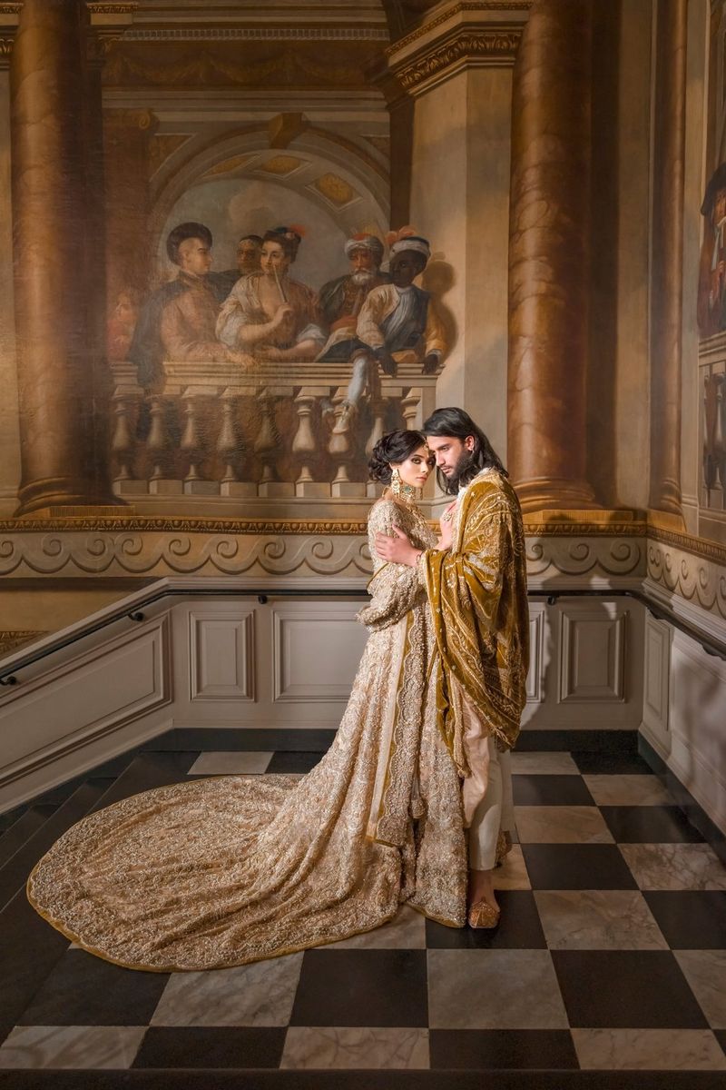 Een bekroonde afbeelding van een rijk uitgedost koppel in zijaanzicht onder een schilderij van mensen op een balkon. Gefotografeerd met een Canon EOS R5 door fotograaf Sanjay Jogia.