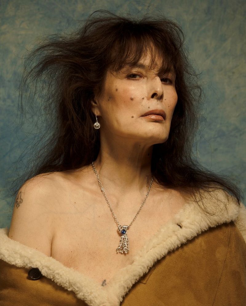 Egy középkorú szokatlan szépségű modell kócos hajjal pózol.