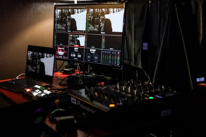 A screen displays the output of a film in black and white, with a mixing desk in the foreground.
