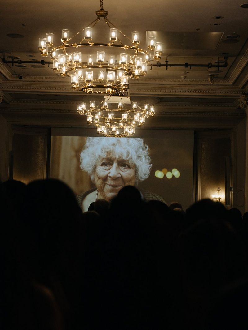 An image of actor Miriam Margolyes on screen at Raindance Icon Awards 2026, with chandeliers in the foreground.