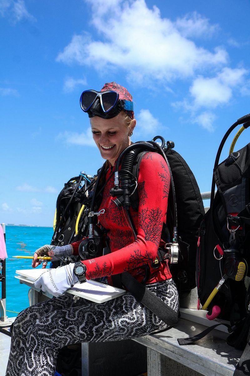 Devon sits on a boat, writing on an underwater slate.
