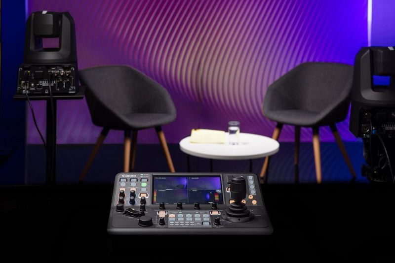 Il controller Canon RC-IP10000 è situato nella parte inferiore dello schermo, affiancato da due telecamere PTZ Canon in uno studio per interviste.