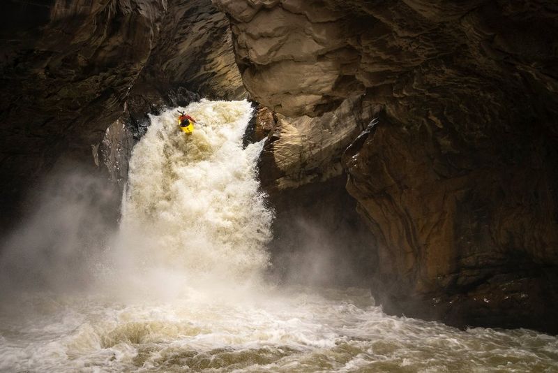 A kayaker speeds down a gushing canyon in low light. Shot on Canon. 