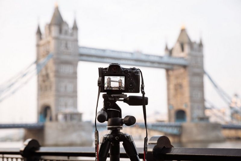  A Canon EOS R5 camera on a tripod, ready to capture wingsuiters flying through London's Tower Bridge, visible in the background.