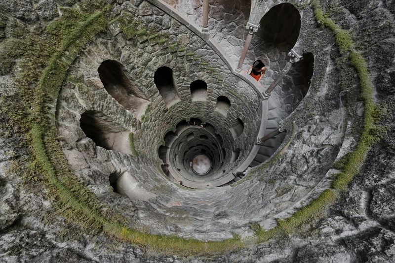 The spiral staircase at Poço Iniciático, or Initiation Well, Portugal, descends in a photo shot from above. Taken with a Canon RF 10-20mm F4L IS STM lens by Joel Santos.
