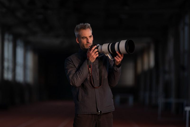 Photographer Julian Finney holding a Canon EOS R3 with a Canon RF 100-300mm F2.8L IS USM lens attached.