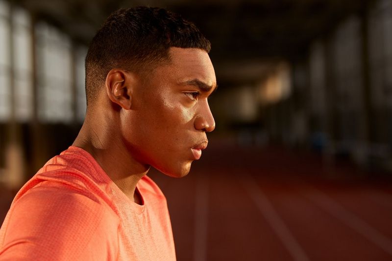 An athlete is captured mid long jump with a sports stadium in the background, in a photo by Julian Finney captured using a Canon RF 100-300mm F2.8L IS USM lens.