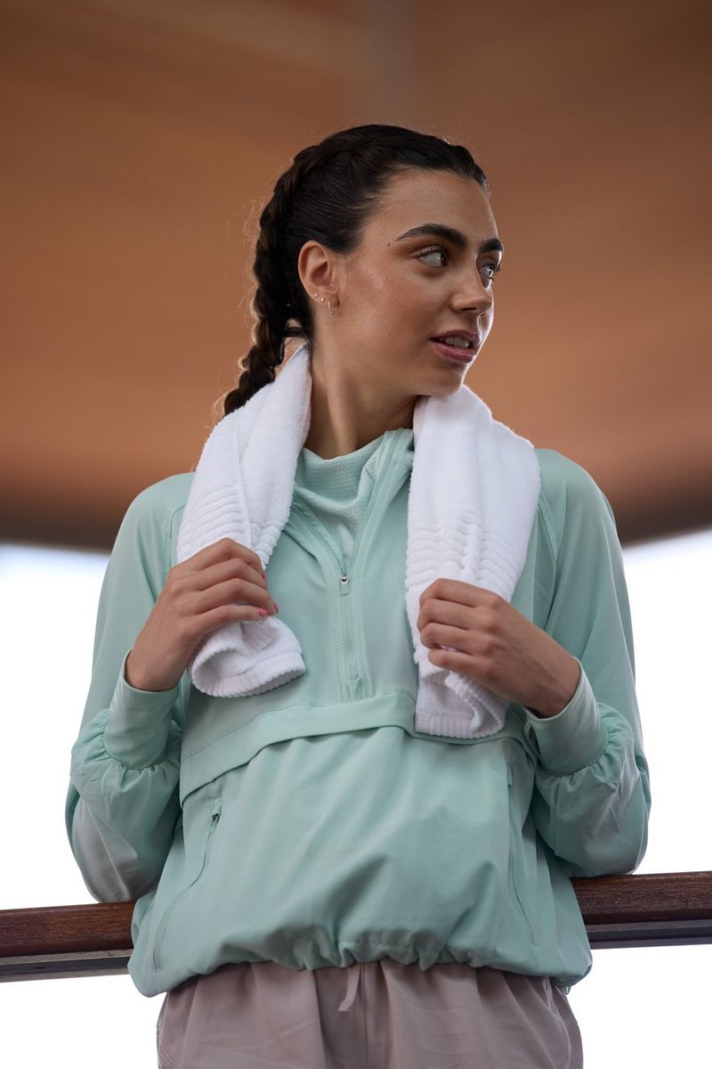 A woman in a tracksuit with a towel around her shoulders looking to the side, taken at a 300mm focal length with a Canon RF 100-300mm F2.8L IS USM lens.