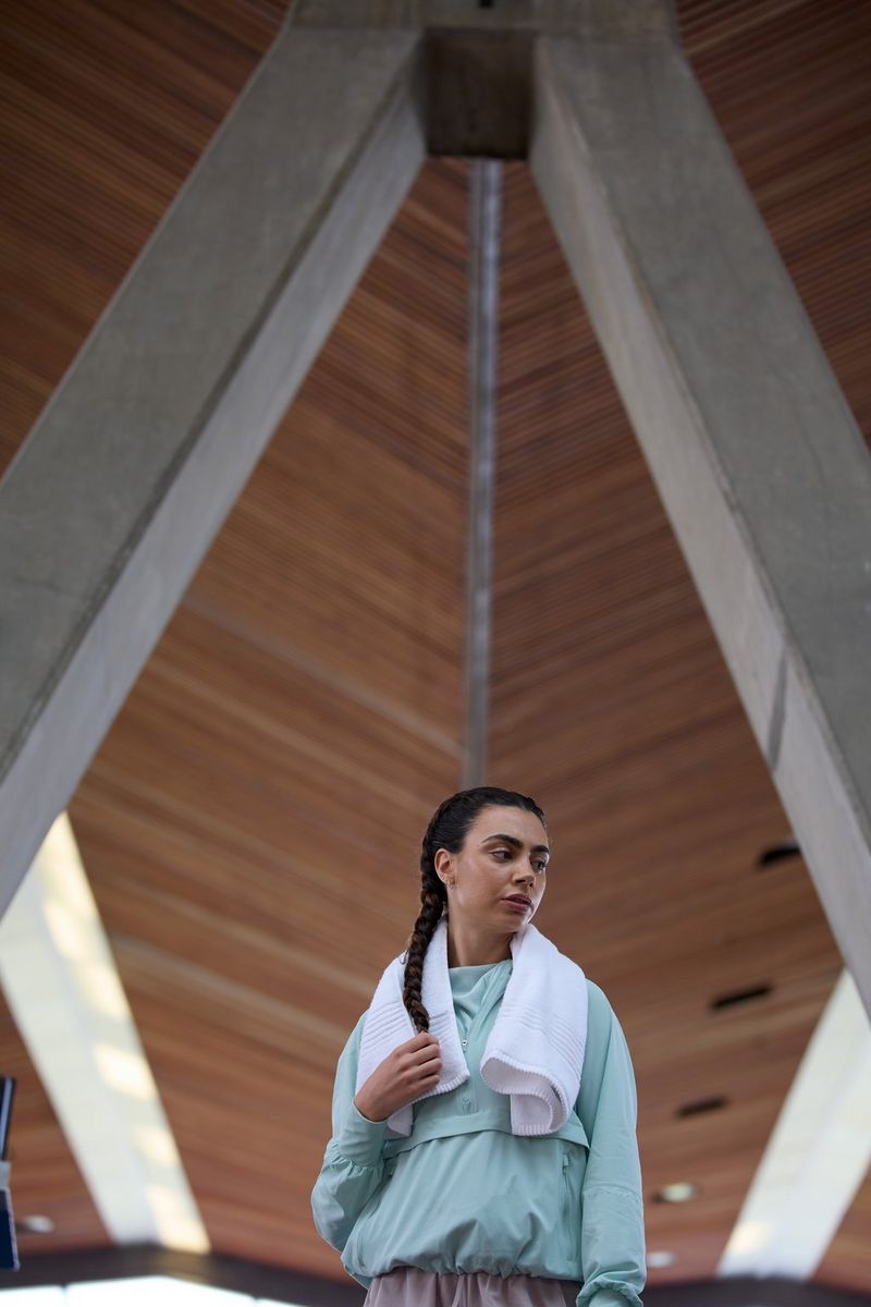 A woman in a tracksuit with a towel around her shoulders looking to the side, taken at a 300mm focal length with a Canon RF 100-300mm F2.8L IS USM lens.