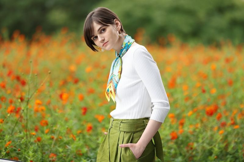 Портрет девушки, стоящей посреди цветочного поля; снято с помощью объектива Canon RF 135mm F1.8L IS USM.