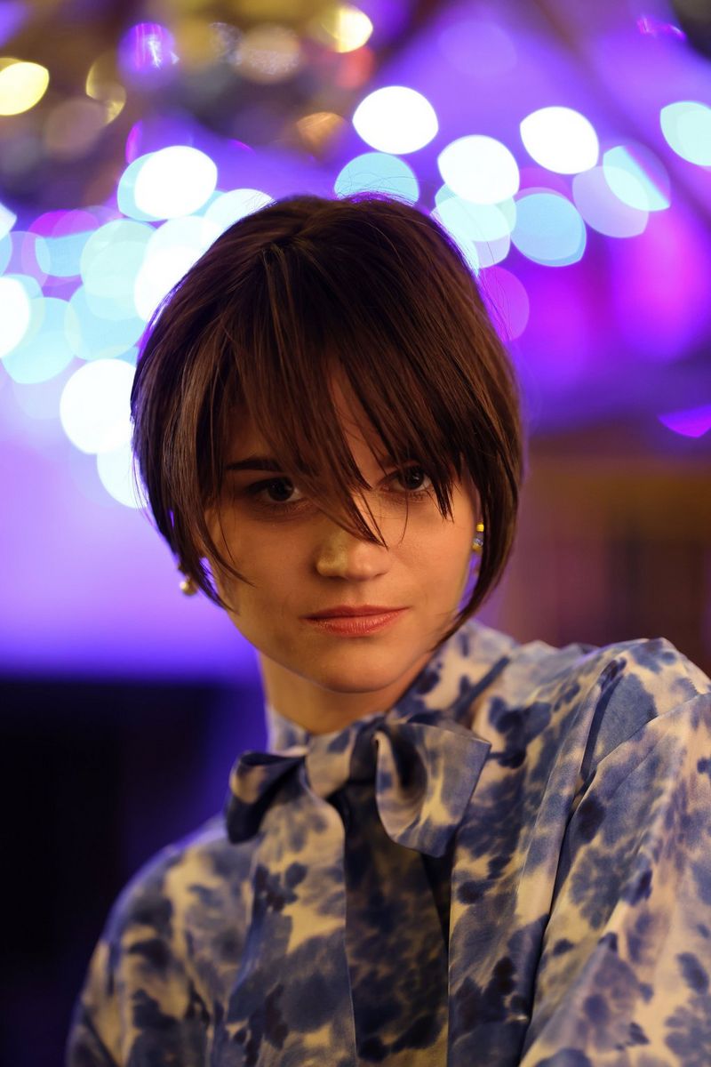 Slabo osvetlený portrét ženy na pozadí výrazného bieleho a bledomodrého kruhového efektu bokeh.