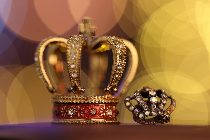 A close-up of two jewelled crowns, taken using using the largest aperture of the Canon RF 135mm F1.8L IS USM lens to create a beautifully defocused backdrop.