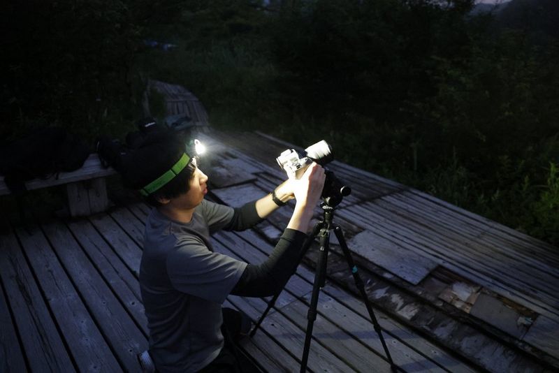 Tatsuro Watanabe, de Canon, responsable de la conception optique de l'objectif ultra grand-angle RF 14mm F1.4L VCM, règle les paramètres de son appareil photo la nuit à l'aide d'une lampe frontale.