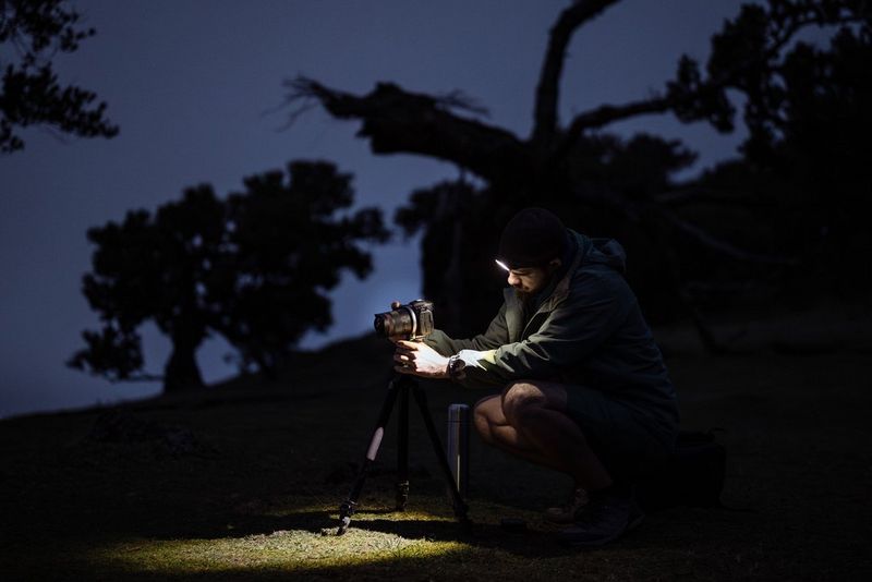 Astrofotograaf Radoslav Sviretsov die 's nachts een hoofdlamp draagt en zijn Canon EOS-systeemcamera afstelt met een RF 14mm F1.4L VCM-objectief.