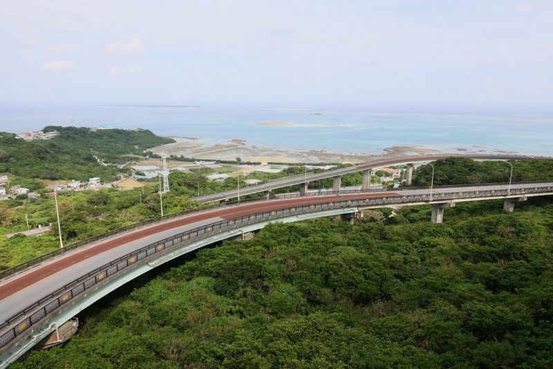 Поглед од високо накај отворено море над бујно зеленило и подигнат пат што го сече. Снимено со кит-објектив Canon RF 24-105mm F4L IS USM.