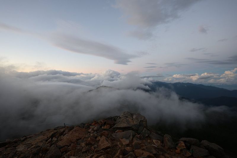 Una vetta di montagna avvolta da nuvole e nebbia, fotografata con un obiettivo Canon RF 16-28MM F2.8 IS STM.