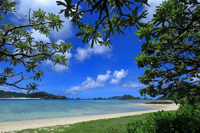 Сончев морски пејзаж со песочна плажа, светлосино небо и острови со густа вегетација во водата. Фотографирано со широкоаголен објектив Canon RF 16mm F2.8 STM.