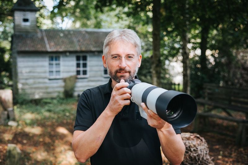 Photographer Guy Edwardes holds a Canon camera, with a Canon RF 200-800mm F6.3-9 IS USM lens attached. 