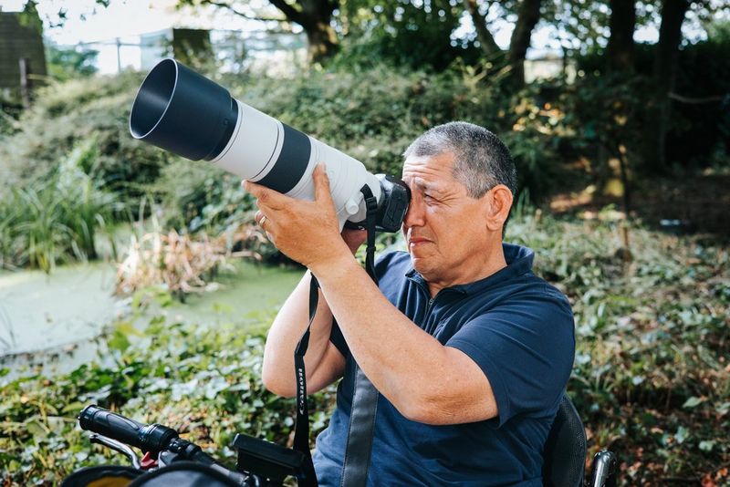 Peter Lau holds up a Canon camera with a Canon RF 200-800mm F6.3-9 IS USM lens attached. 