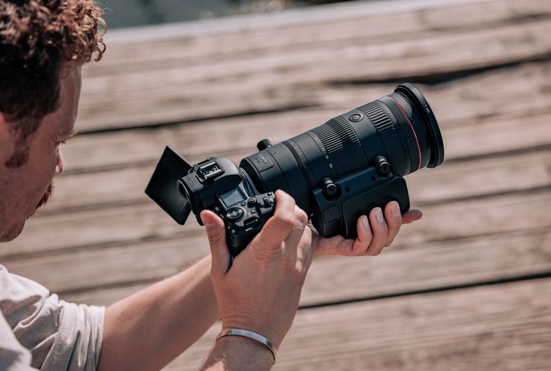 Een gebruiker houdt een Canon-camera vast met daarop een Canon RF 24-105mm F2.8L IS USM Z-objectief waarop een Power Zoom-adapter PZ-E2 is bevestigd.