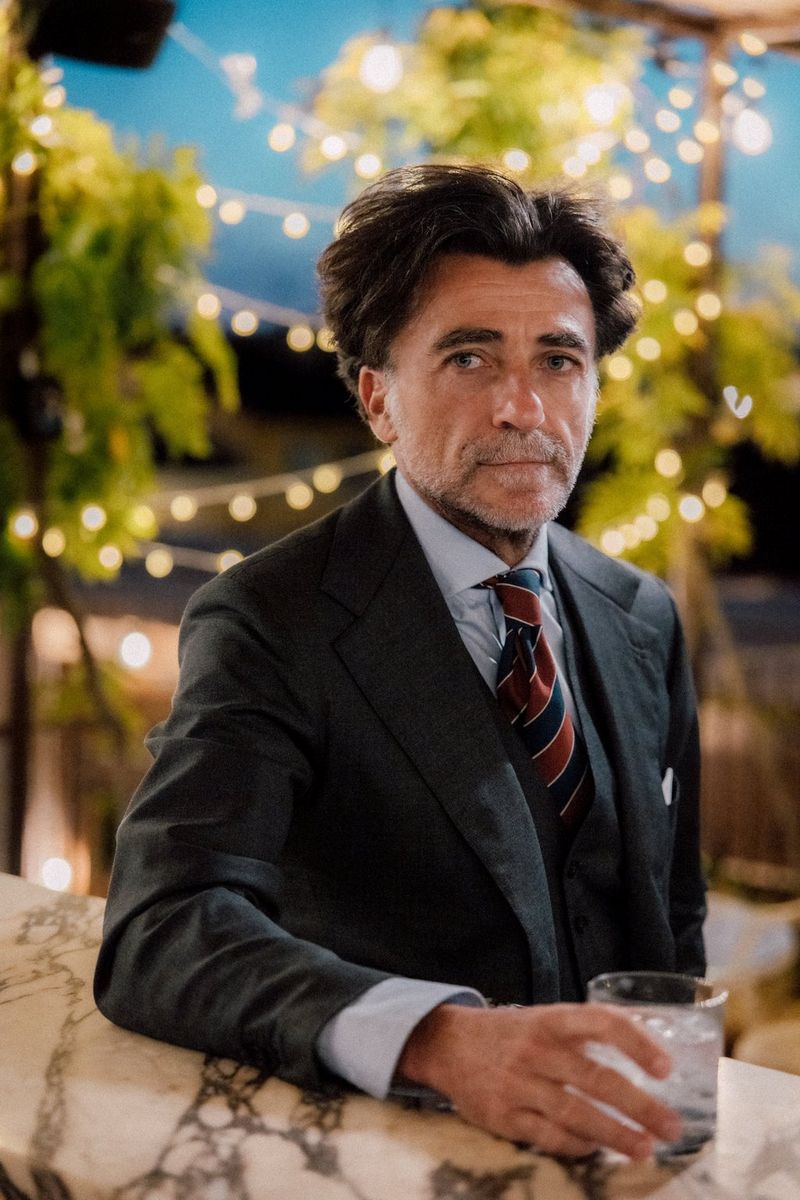 A man in a suit stands on a rooftop terrace with strings of softly blurred lights behind him, in a photo captured with a Canon RF 24-105mm F2.8L IS USM Z lens.