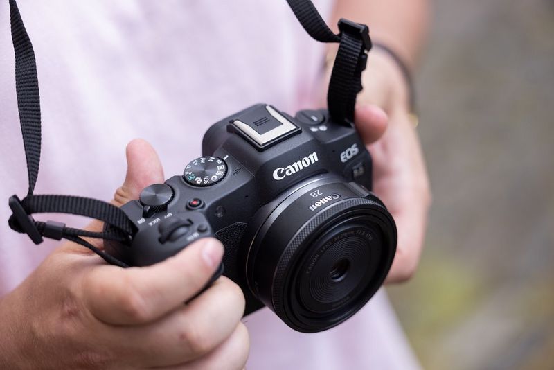 A pair of hands holding a Canon EOS R8 with a Canon RF 28mm F2.8 STM lens, commonly used in street photography. 