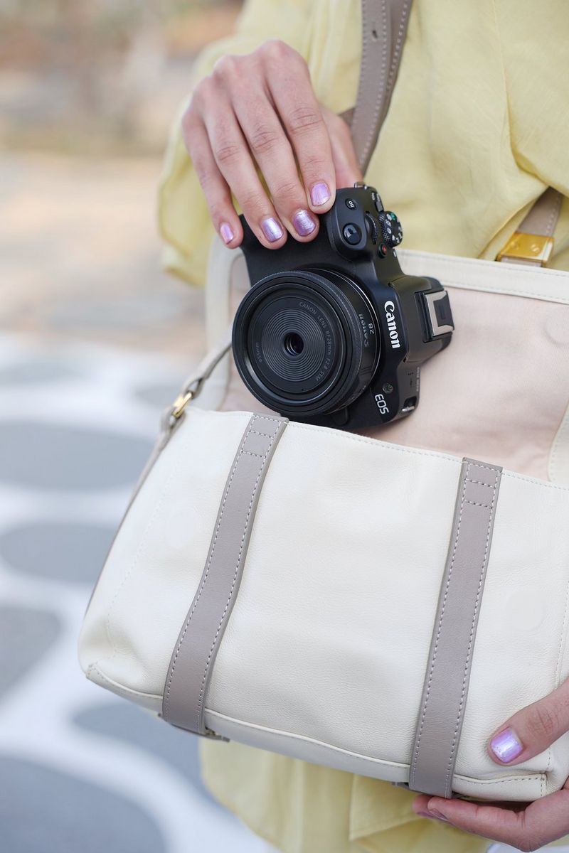 אדם מחליק לתיק שלו מצלמת Canon עם עדשת Canon RF 28mm F2.8 STM.