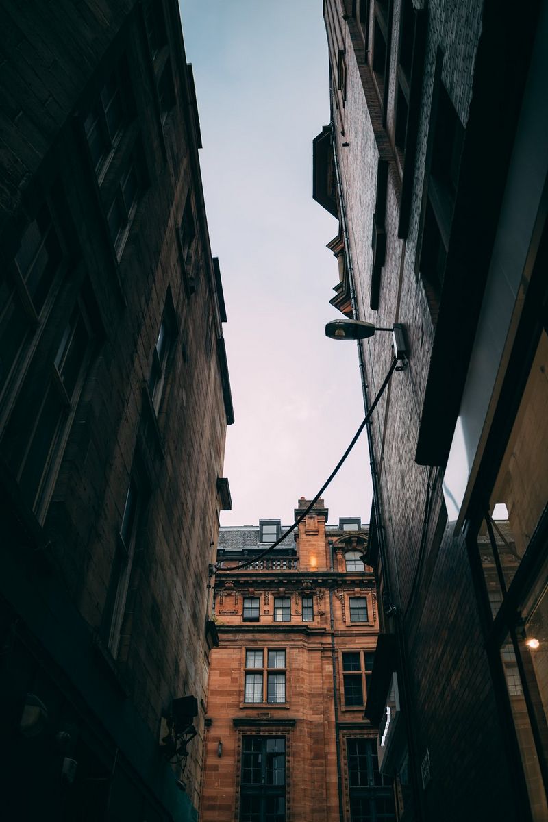A view through a narrow alleyway between two buildings, looking towards another building opposite and the sky above, taken with a Canon RF 28mm F2.8 STM prime lens.