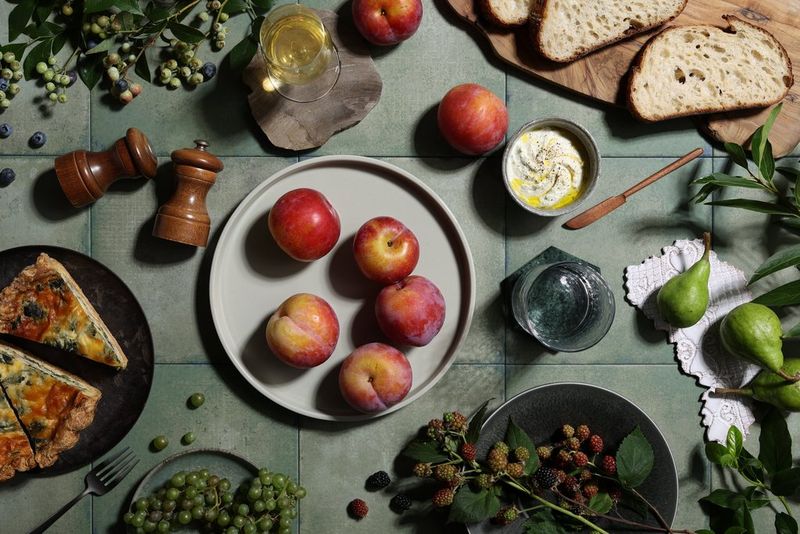 Canon RF 45mm F1.2 STM objektívvel készült felülnézeti ételfotó, amelyen quiche, nektarin, szőlő, körte, kenyérszeletek és hummusz látható.