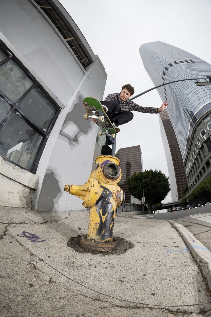 A skateboarder jumps over a yellow fire hydrant on a street in Los Angeles, photographed with a Canon fisheye lens.