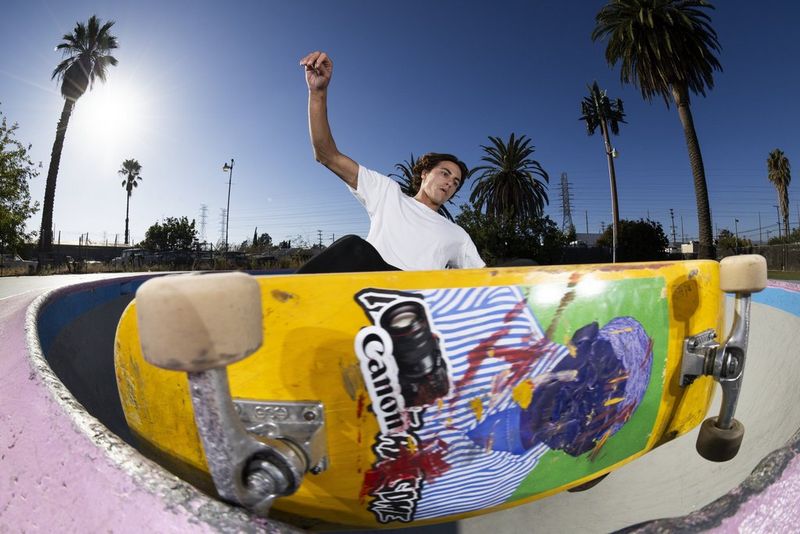 A fisheye image of a skateboarder on the rim of an empty swimming pool, with the skateboard passing close the front of the RF 7-14MM F2.8-3.5L FISHEYE STM lens.