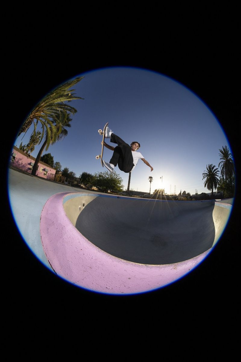 A circular fisheye image of the skateboarder in mid-air above the empty swimming pool at the Pink Motel in Los Angeles, captured using the RF 7-14MM F2.8-3.5L FISHEYE STM lens.