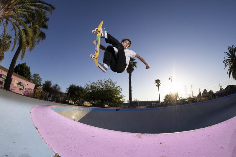 A skateboarder grabs his skateboard in mid-air above an empty swimming pool at the Pink Motel in Los Angeles, captured using the RF 7-14MM F2.8-3.5L FISHEYE STM lens.