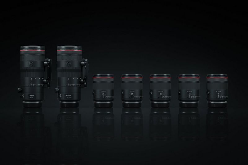 Família de objetivas RF híbridas da Canon, duas de zoom e cinco de distância focal fixa, fotografadas sob um fundo negro.