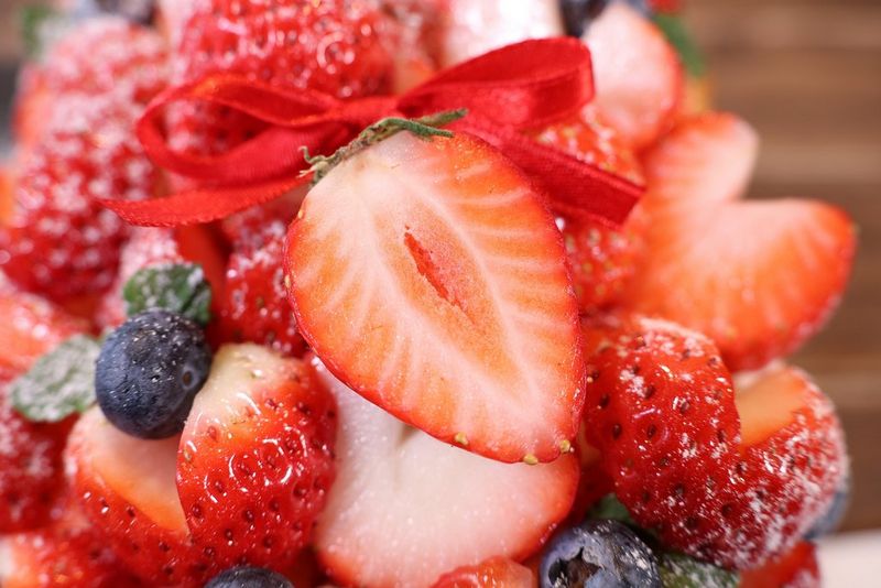 Деталізований знімок нарізаної полуниці на купі інших ягід, зроблене за допомогою об’єктива Canon RF-S 18-150mm F3.5-6.3 IS STM.