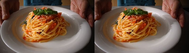 Het linker- en rechter stereoscopische beeld van iemand die een bord spaghetti bolognese met basilicumblaadjes vasthoudt.