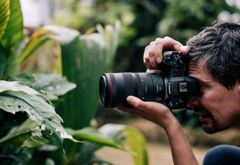 A photographer shoots an insect with a Canon EOS R5 camera and a Canon RF 100mm F2.8L Macro IS USM lens.