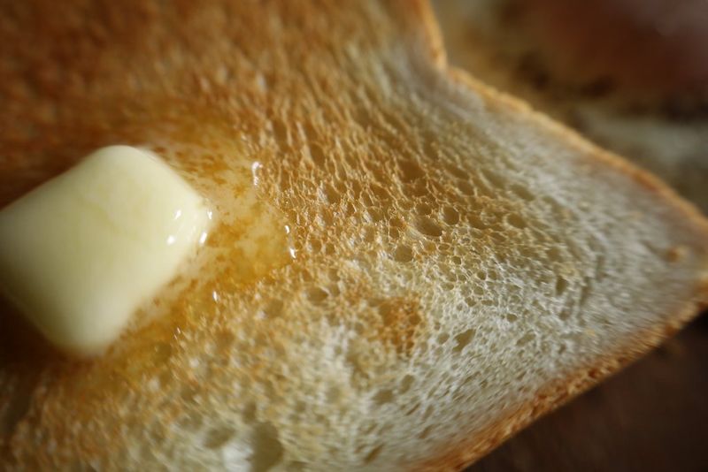 Тост из белого хлеба с небольшим куском тающего масла, съемка крупным планом.