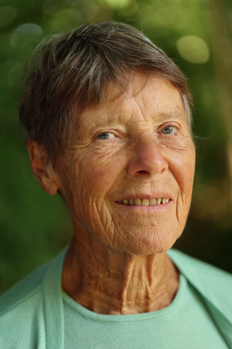 Portret starije osobe s kratkom kosom, u blijedo-tirkiznoj odjeći.