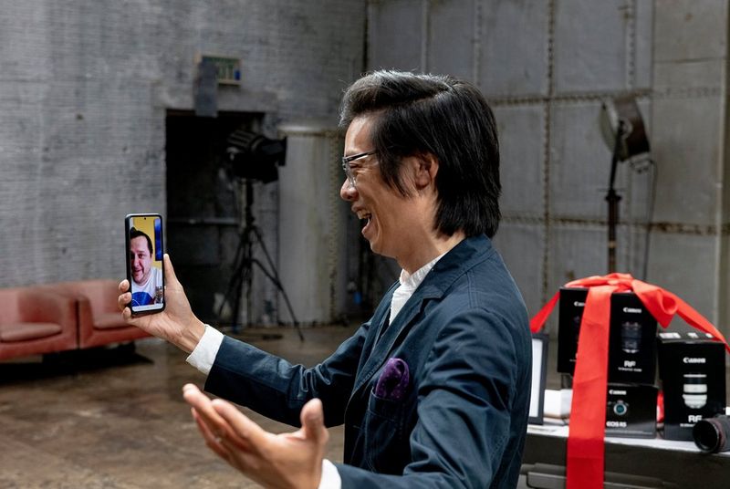 Un homme sourit avec son bras tendu alors qu'il parle à un autre homme visible sur l'écran de son smartphone.