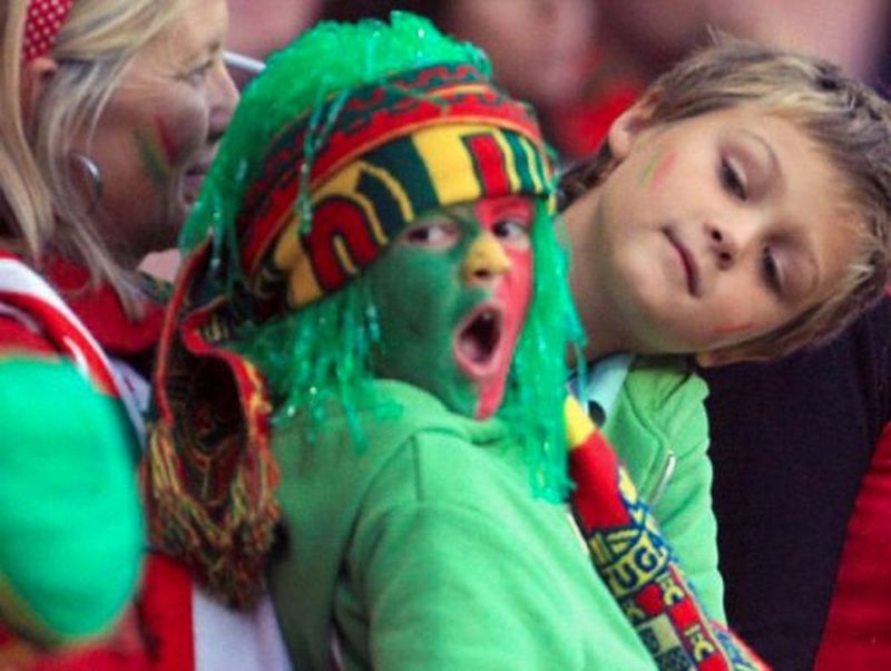 A young boy with face paint in the colours of the Portuguese flag with a young Jerónimo Portela in the crowd  