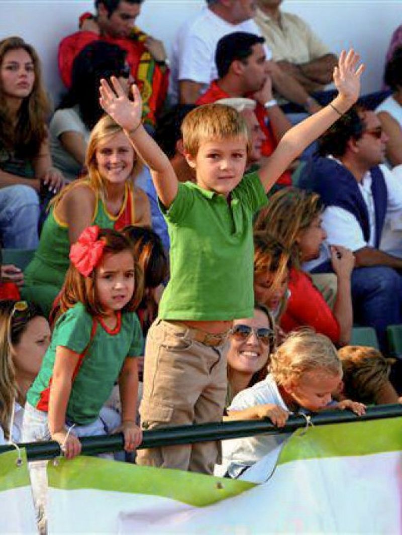 A young Jerónimo Portela stands with his arms in the air among other Portugal rugby supporters in a stadium