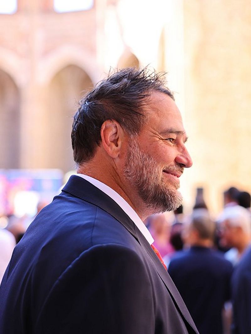 Con indosso un abito, David sorride alla cerimonia in vista della Coppa del Mondo di Rugby 2023