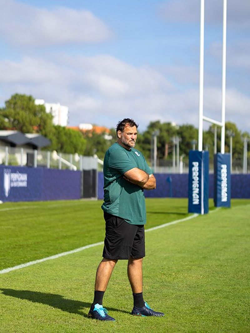 In piedi con le braccia incrociate, David guarda la sessione di allenamento