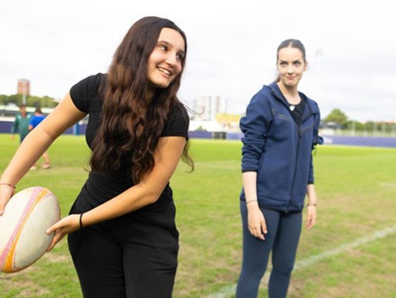 Un giovane giocatore di rugby lancia la palla mentre un altro guarda