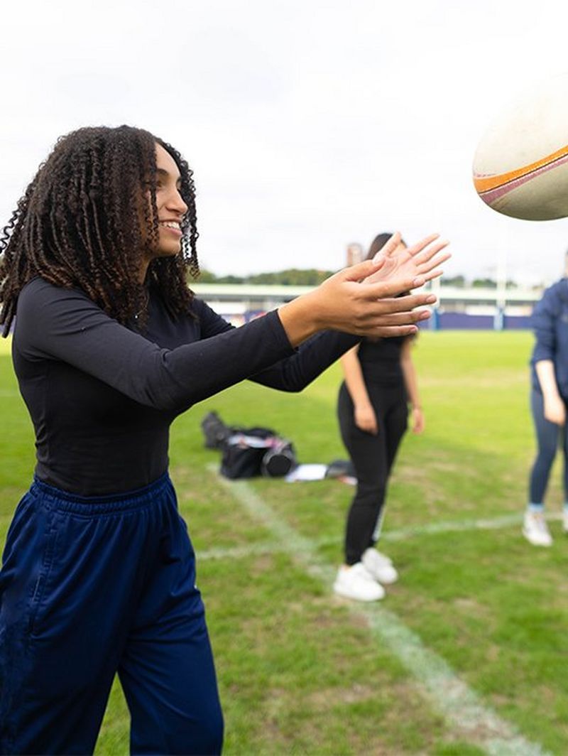 Una ragazza con le braccia in alto pronta a prendere la palla in volo