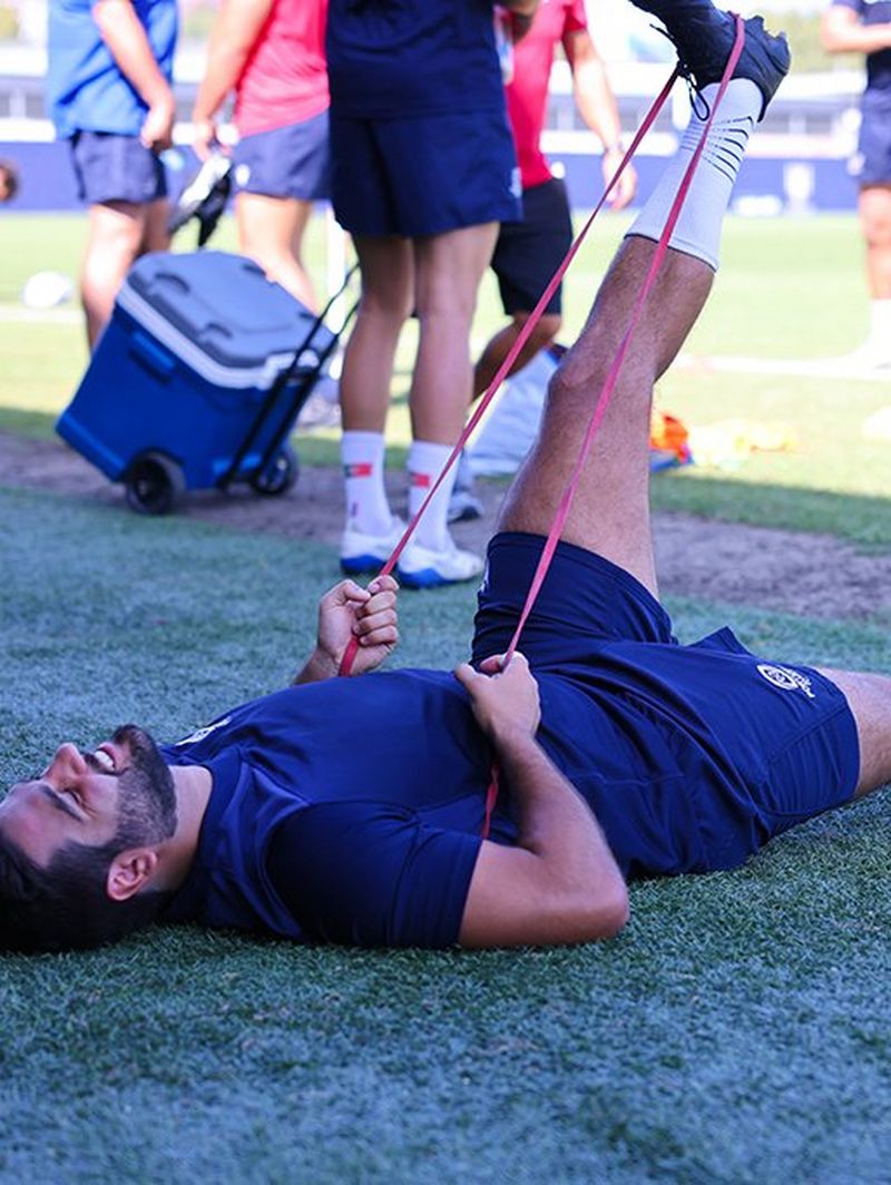 João Granate lies on his back and uses a resistance band to stretch