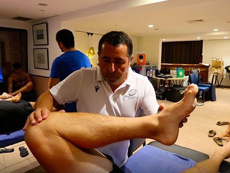 In the treatment room, José Rodrigues treats a player’s knee by testing the bend in the joint 